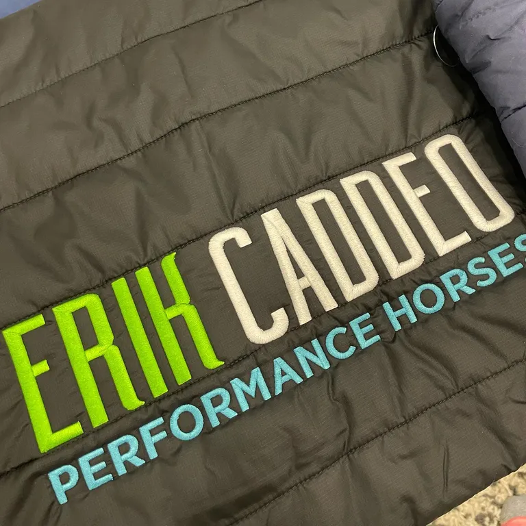 Multi-color company logo embroidered on a black quilted jacket