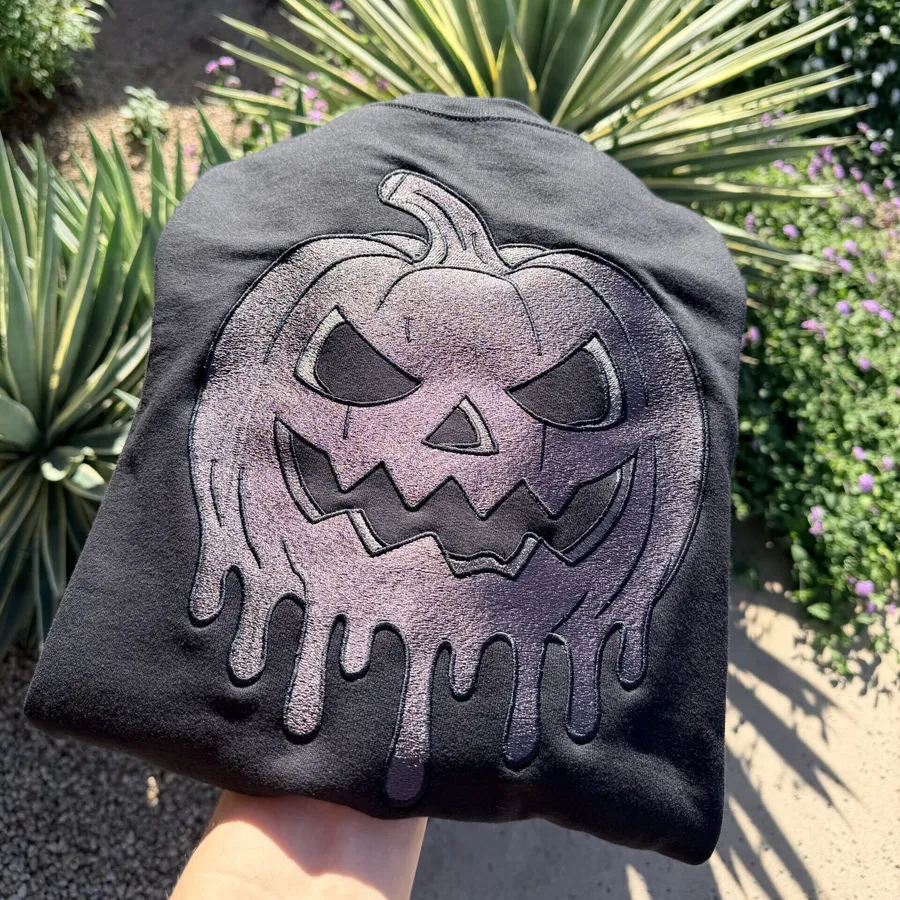 Black crewneck sweatshirt with metallic melting jack-o-lantern embroidery